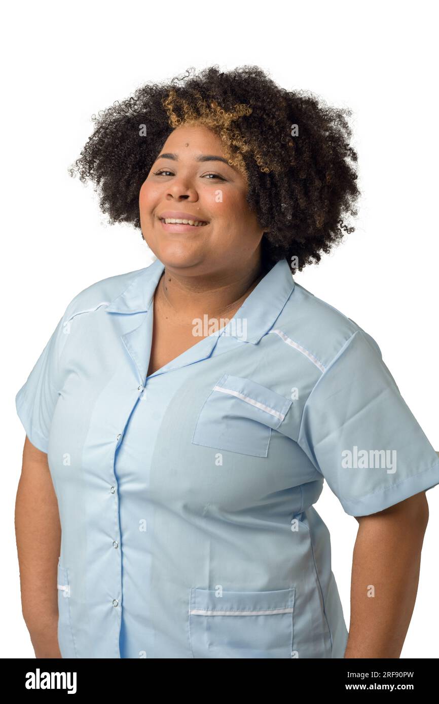 Taille hoch vertikales Porträt einer glücklichen jungen afro-lateinischen Ärztin in blauer Uniform, die in die Kamera schaut, vor weißem Hintergrund. Stockfoto