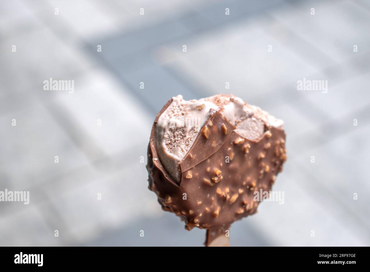 Schokoladeneis mit Haselnuss und klassischer Milchschokolade. Machen Sie Fotos mit einem verschwommenen öffentlichen Ort als Hintergrund Stockfoto