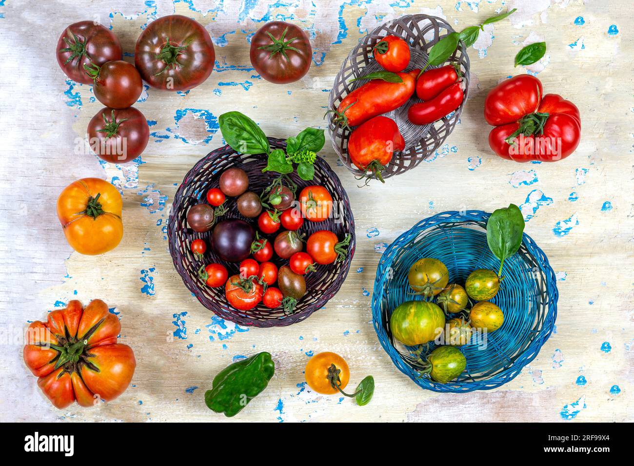 Tomaten in Körben, von oben gesehen, auf einem alten cremefarbenen Brett mit blauem Fleck platziert. Stockfoto