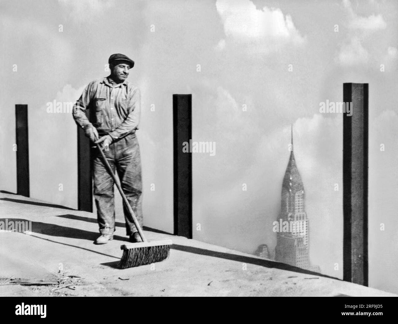 New York, New York: ca. 1931. Ein Arbeiter, der den höchsten Bürgersteig der Welt, das 81. Stockwerk des Empire State Building, das höchste Gebäude der Welt, bis zum Gipfel fegt, von dem das größte biegesteife „Los Angeles“ versuchen wird, anzulegen. Dieses Foto wurde 1.248 Meter über der Straße gemacht. Stockfoto