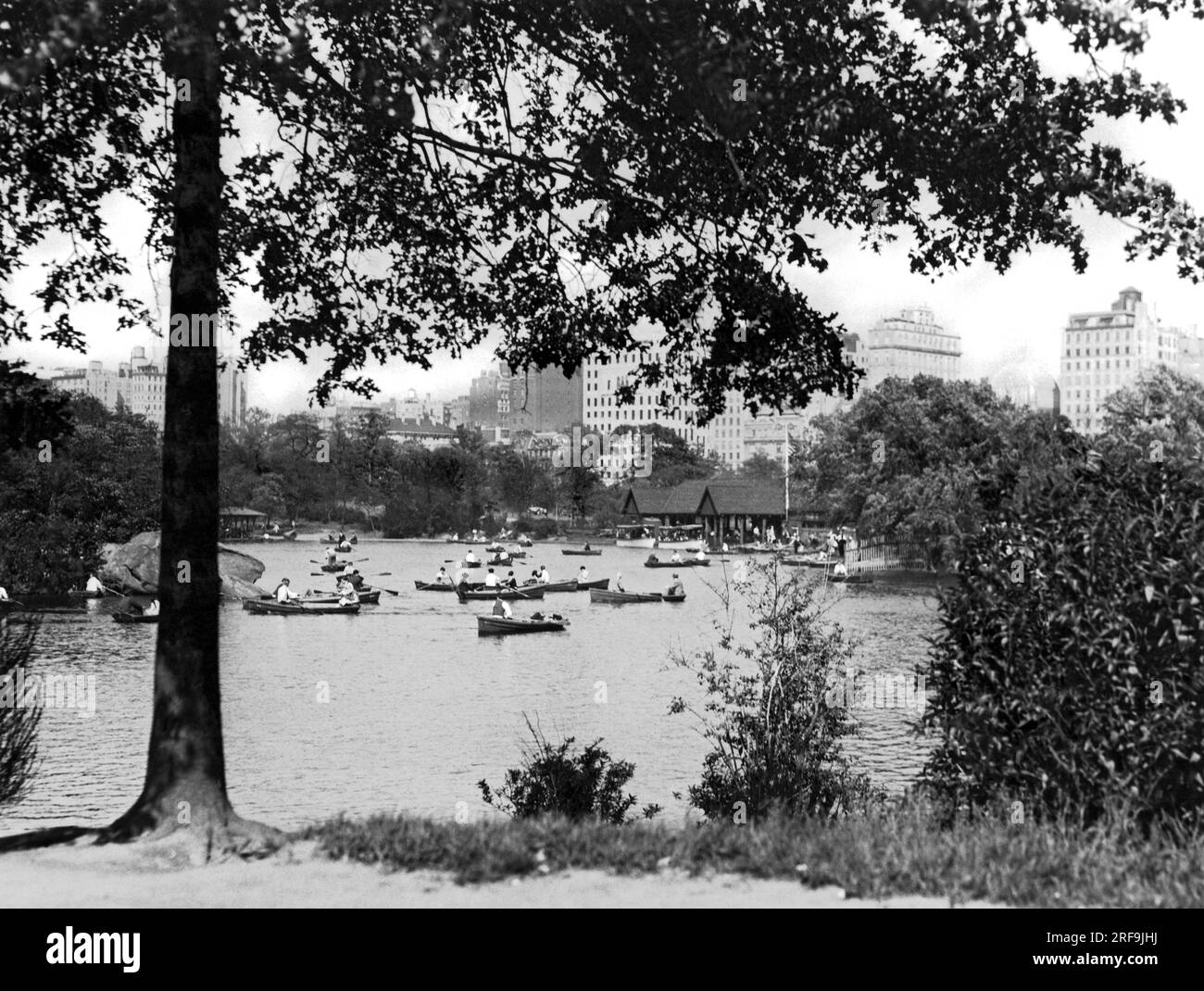 New York, New York: ca. 1928 Bootsfahrer genießen einen milden Tag in Manhattan, während sie um den See in der Nähe des Boathouse im Central Park rudern. Boote können gemietet werden und Essen kann man im Bootshaus kaufen. Stockfoto