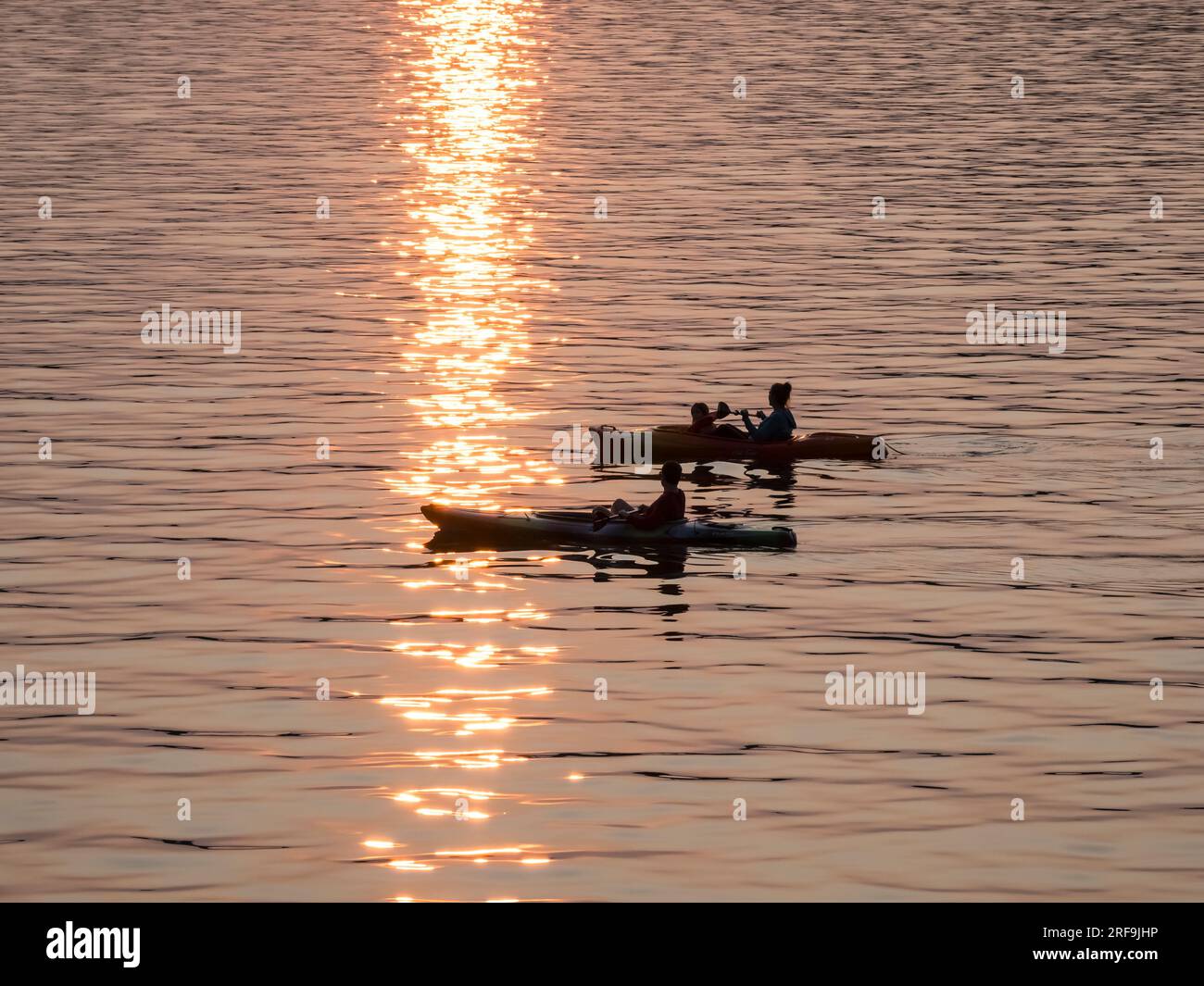 Kajakfahren im Lake Superior mit der goldenen Sonne, die im Wasser funkelt. Stockfoto