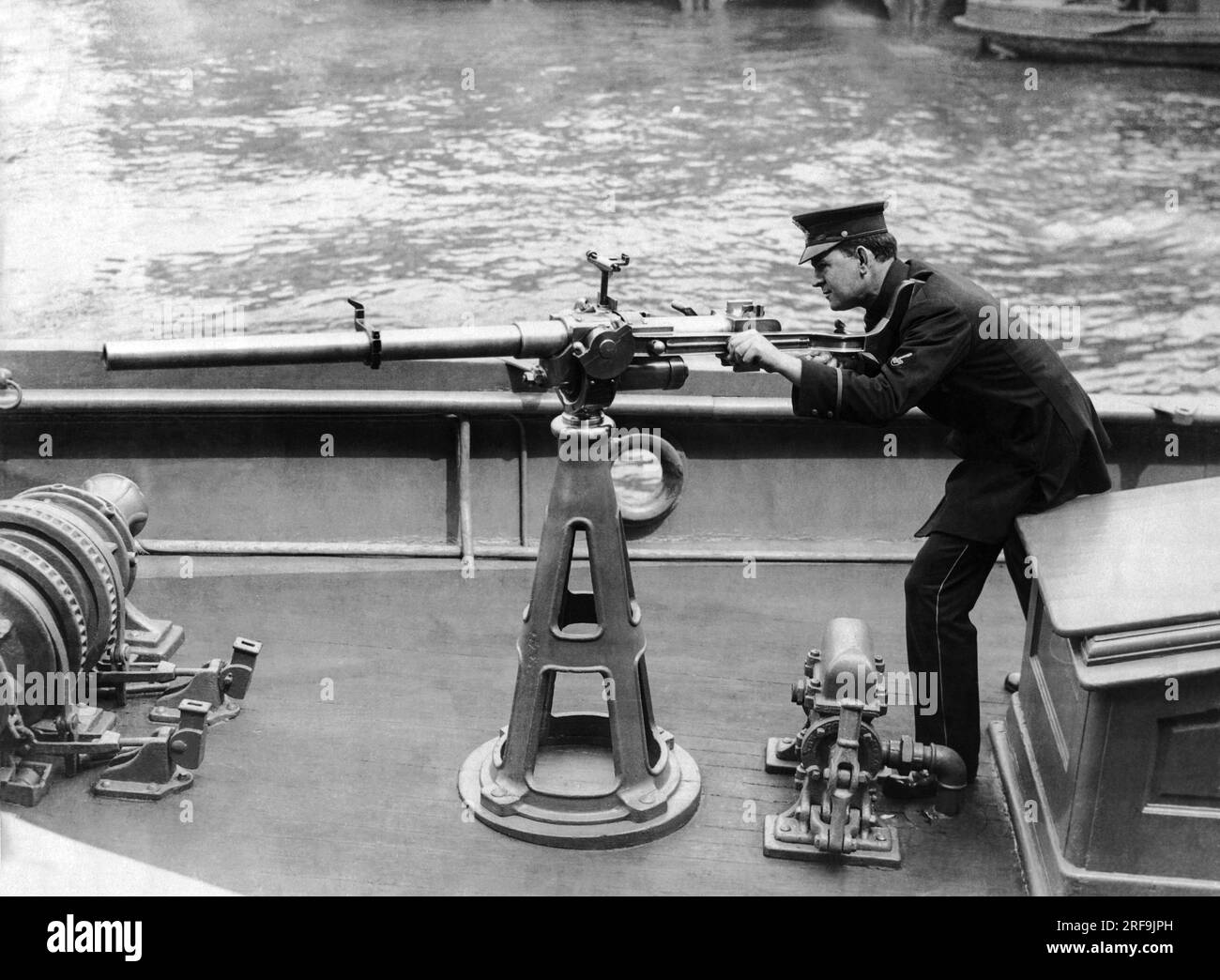 New York, New York: 16. Februar 1917 Ein Polizist aus New York City managt das 1-Pfund-Gewehr Hotchkiss 37mm, das auf dem Deck des Polizeiboots 'Patrol' im Hafen von New York montiert ist. Stockfoto