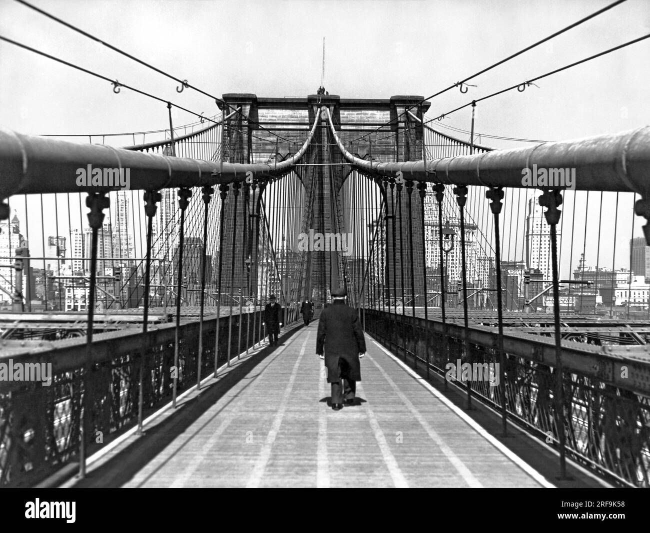 New York, New York: 6. April 1938 Ein gemütlicher Spaziergang über eine der schönsten Brücken der Welt, die berühmte Brooklyn Bridge, die 1883 erbaut wurde. Stockfoto