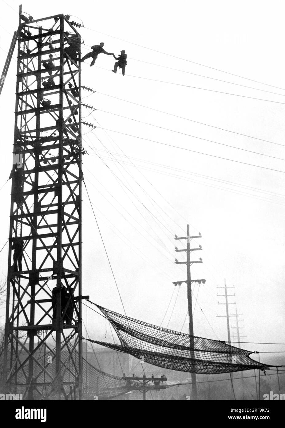 New York, New York: 4. Dezember 1939 Ein Polizist greift einen Mann an Hochspannungsleitungen, bevor er seine Sprungdrohung ausführen kann. Die Leitungen haben normalerweise 33.000 Volt, wurden aber für zwei Stunden während der Resvue abgeschaltet, wodurch der Zugverkehr auf Long Island zunahm. Die Sicherheitsnetze waren unten verteilt. Stockfoto