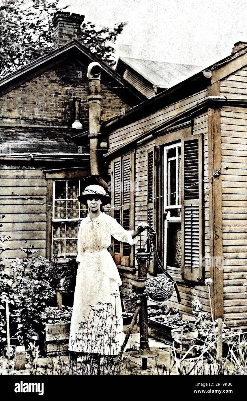 Eine Frau, die an einer Wasserpumpe steht, etwa 1910. Stockfoto