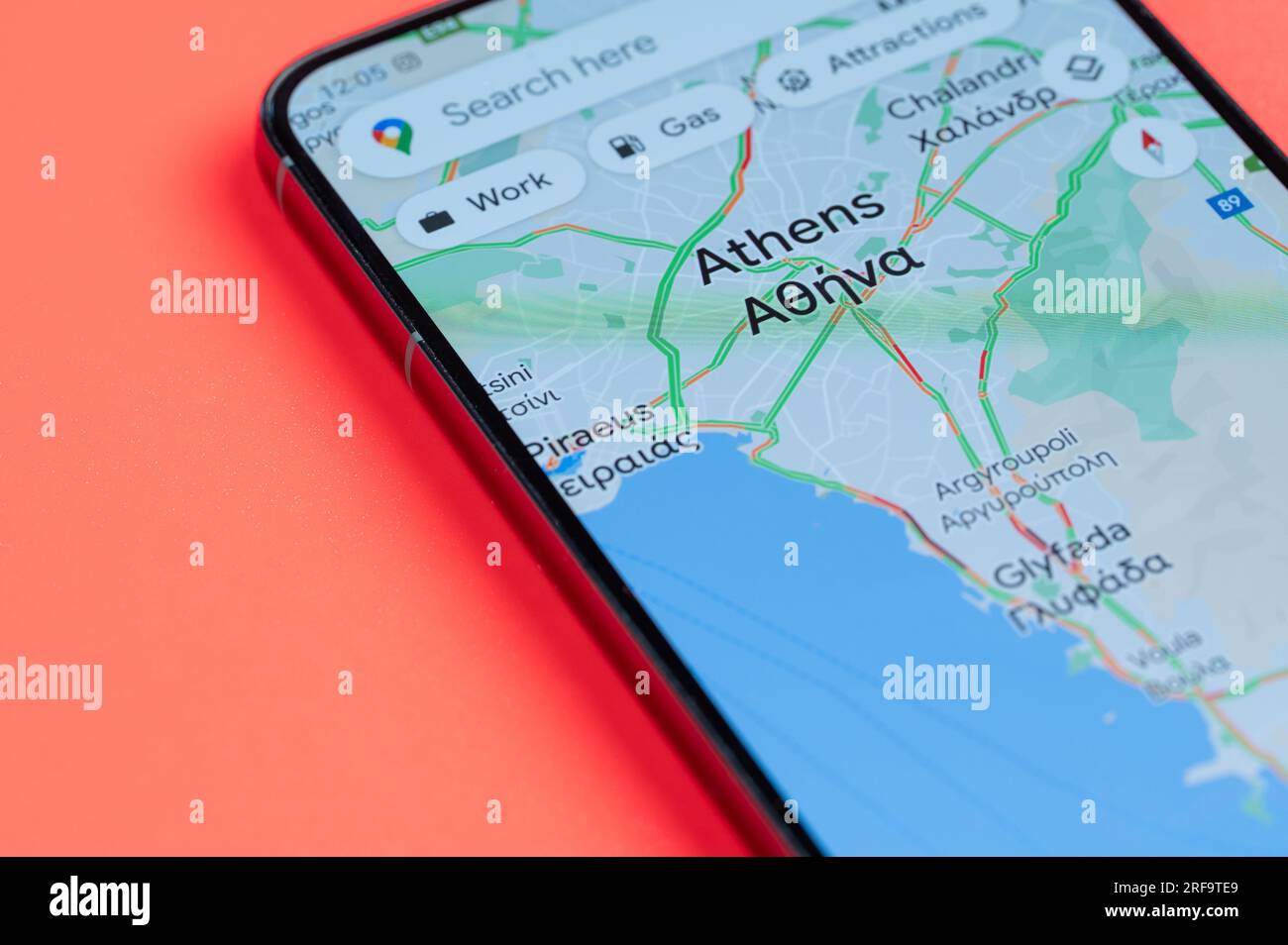 New York, USA - 21. Juli 2023: Verteilung des Autoverkehrs in Athen auf google-Karten auf dem Smartphone-Bildschirm Nahaufnahme mit rotem Hintergrund Stockfoto