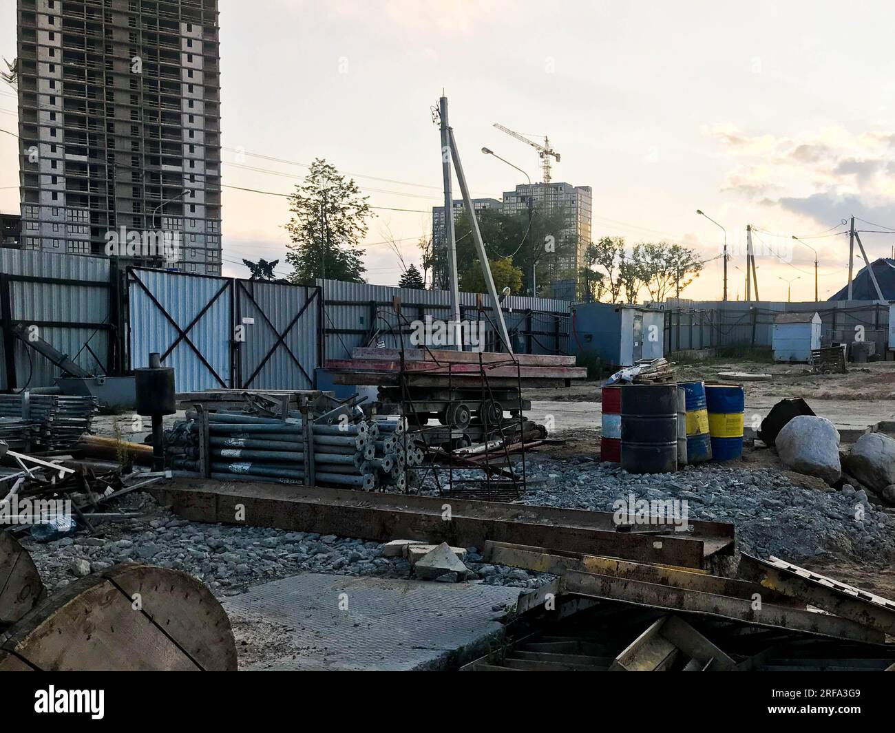 Innenansicht einer großen industriellen Baustelle hinter einem Zaun mit Werkzeugen, Rohrleitungen und Baumaterialien, auf denen neue Häuser gebaut werden Stockfoto