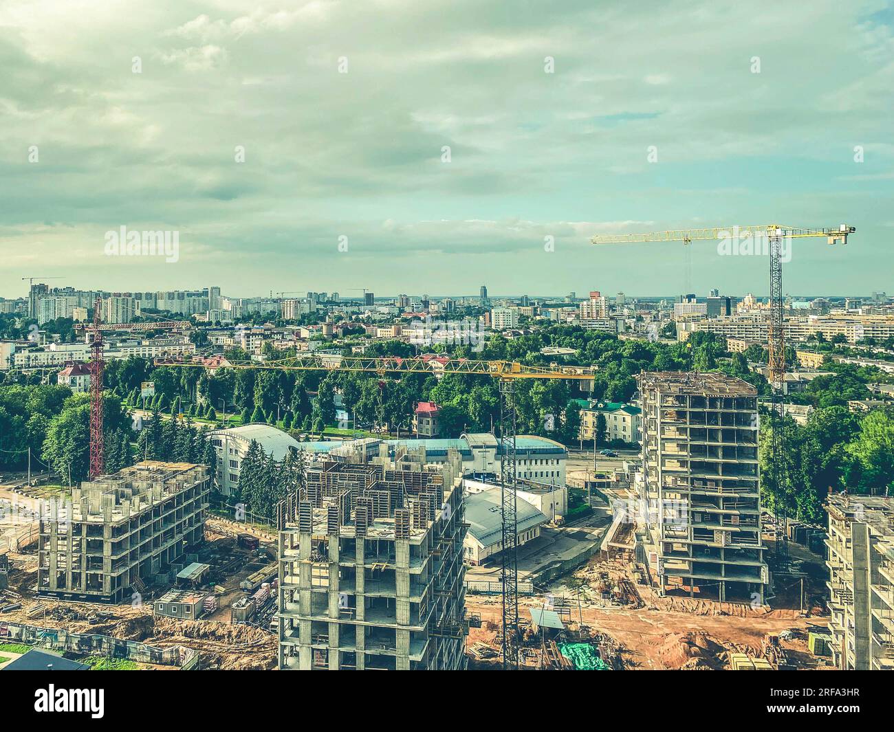 Bau mehrstöckiger Gebäude im Stadtzentrum. Hochhäuser aus Betonblöcken und Betonplatten. Schwerer, gelber Metallkran hebt Gebäude ma Stockfoto