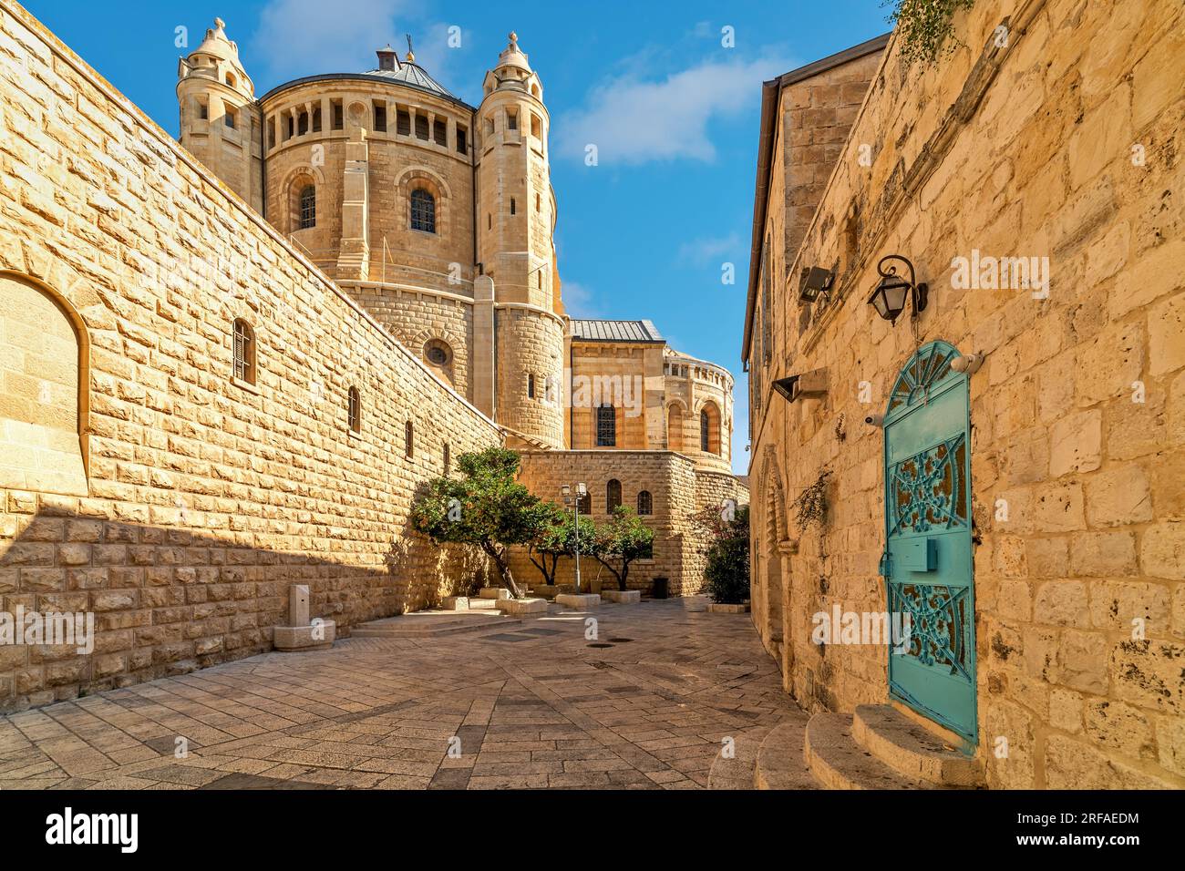 Blick auf die schmale Straße inmitten der alten Mauern wie die Dormition Abbey unter blauem Himmel im Hintergrund in der Altstadt von Jerusalem, Israel. Stockfoto