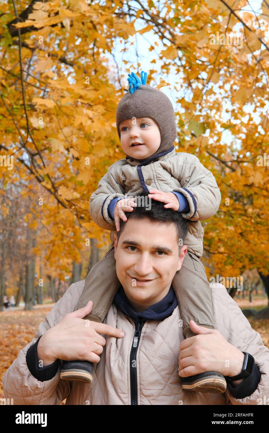 Porträt eines Vaters, der seinen süßen kleinen Sohn auf den Schultern trägt, Baby und Daddy mit Vergnügen, Zeit zusammen im Freien zu verbringen, glückliches Familienleben. Verti Stockfoto