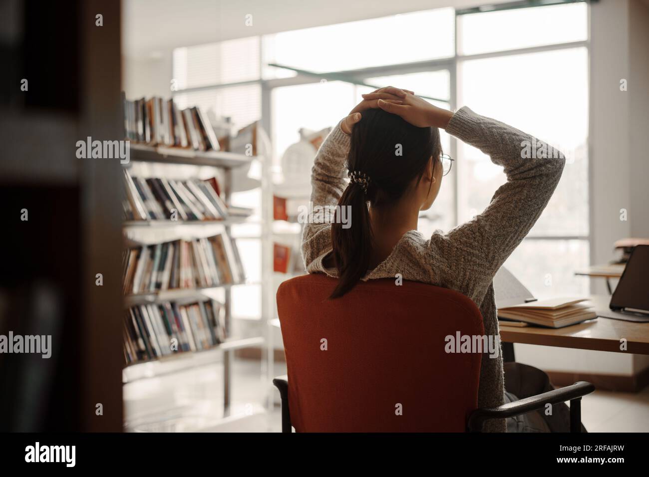 Asiatische Studentin liest Bücher in der Bibliothek an der Universität. Junge, stressmüde Mädchen haben Probleme beim Lernen. Traurigkeitskonzept Stockfoto