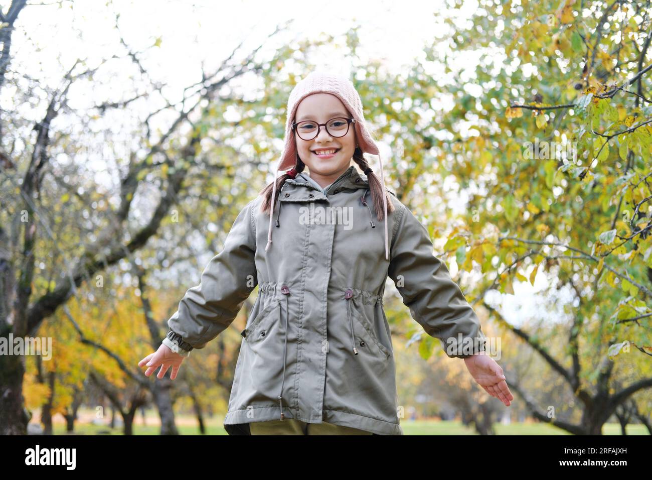 Mädchen spielt Pilotenflugzeug, Handflügel im Herbstpark. Horizontales Foto Stockfoto