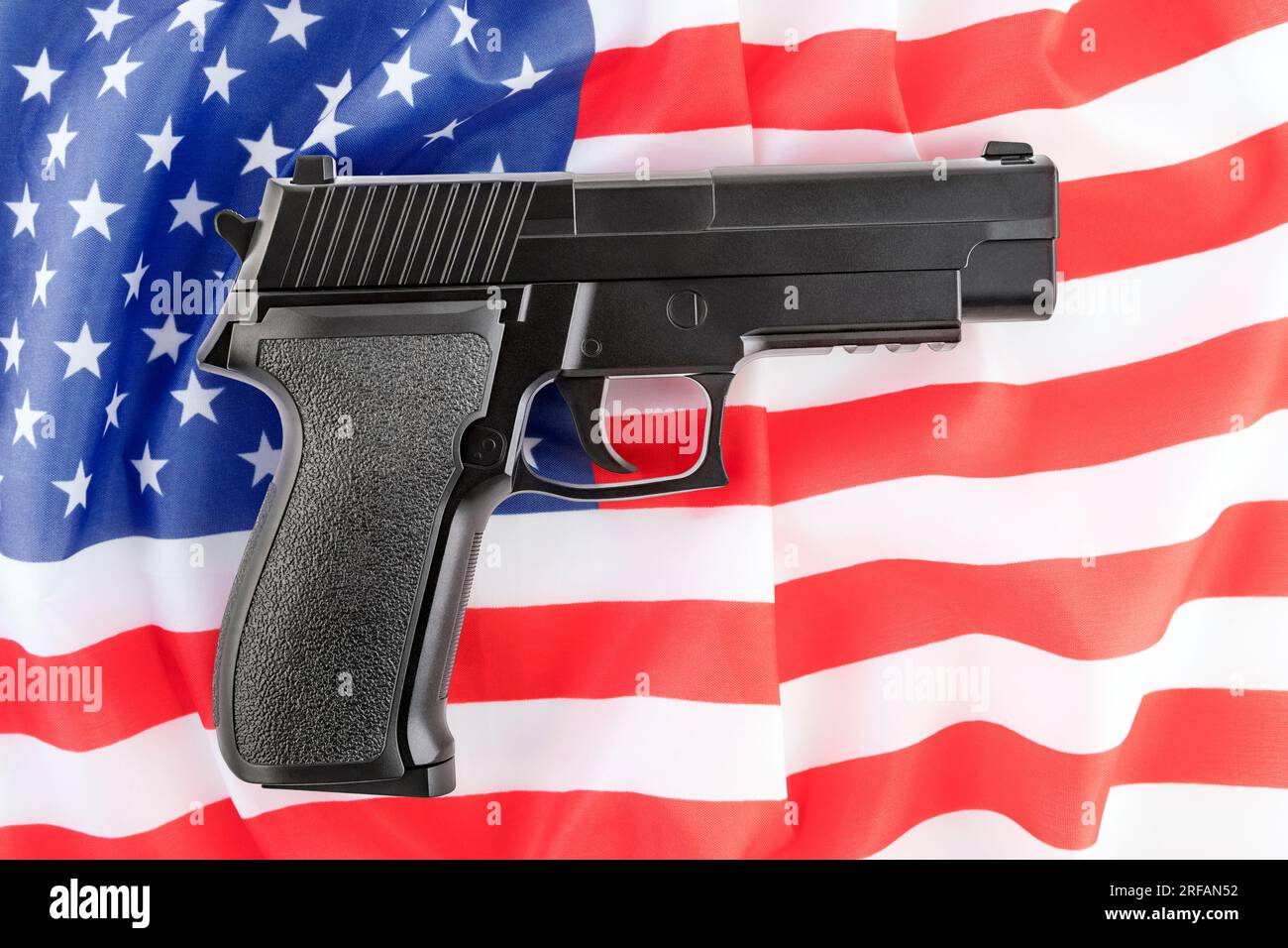 Schwarze Pistole über der amerikanischen Flagge. Debatte über die Beschränkung von Schusswaffen. Stockfoto