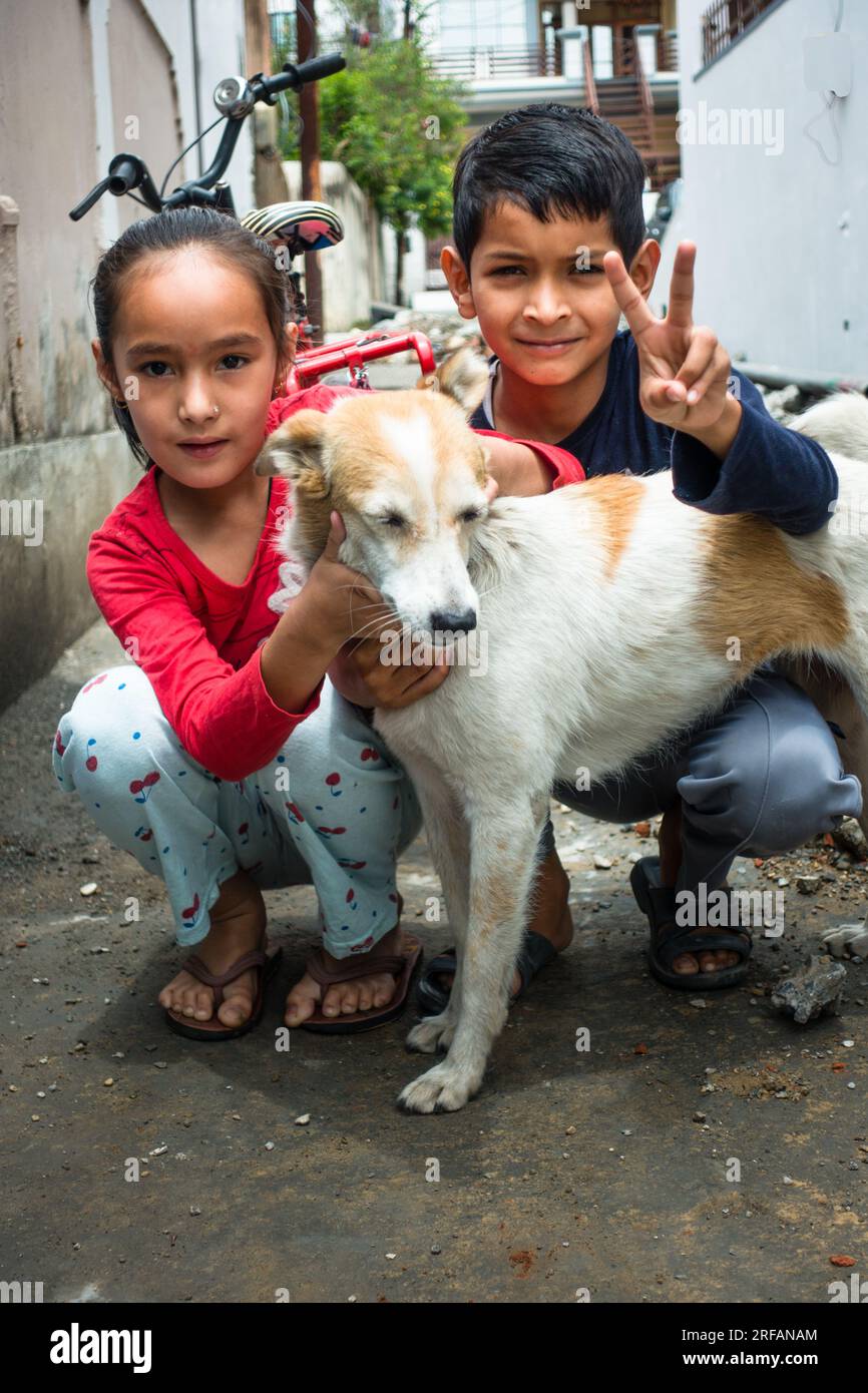 Oktober 14. 2022 Uttarakhand, Indien. Junge indische Geschwister, ein Bruder und eine Schwester, spielten fröhlich mit einem Hund. Herzerwärmender Moment, in dem die Familie eine Beziehung knüpft Stockfoto