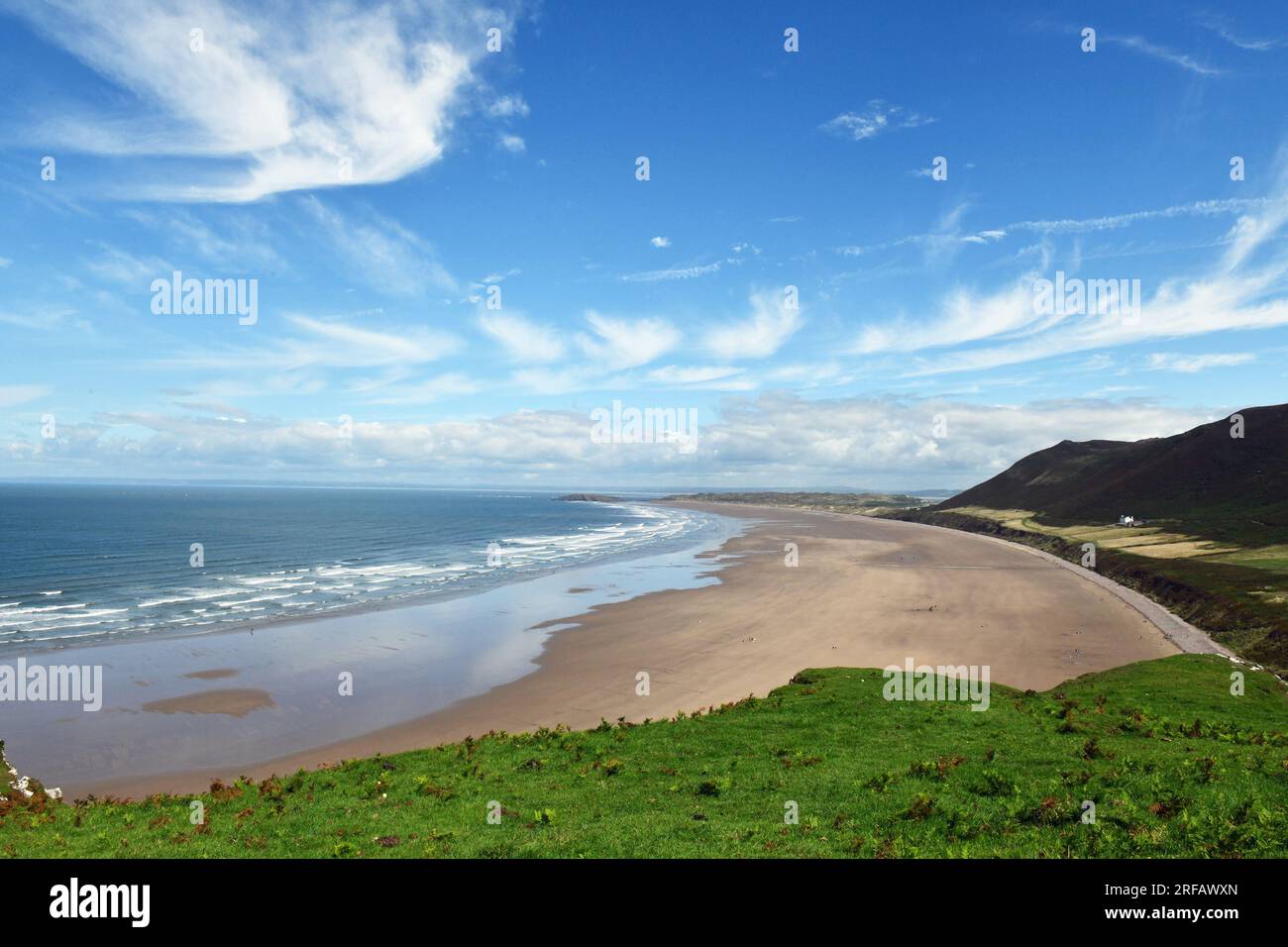 Blick von Rhossili über Rhossili Beach/Bay an einem sonnigen Augusttag auf der Halbinsel Gower mit den Rhossili Downs dahinter und dem alten Vicarage davor Stockfoto