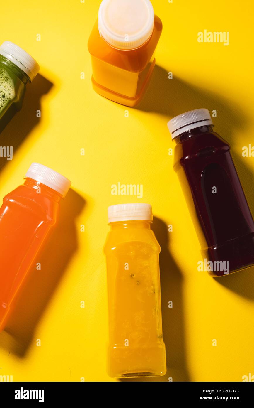 Nahaufnahme von Kunststoffflaschen mit frischem Saft und Kopierbereich auf gelbem Hintergrund Stockfoto