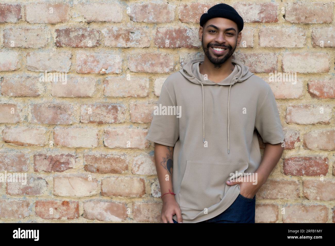 Glücklicher afroamerikanischer Mann mit Mütze und Piercing draußen in der Stadt Stockfoto