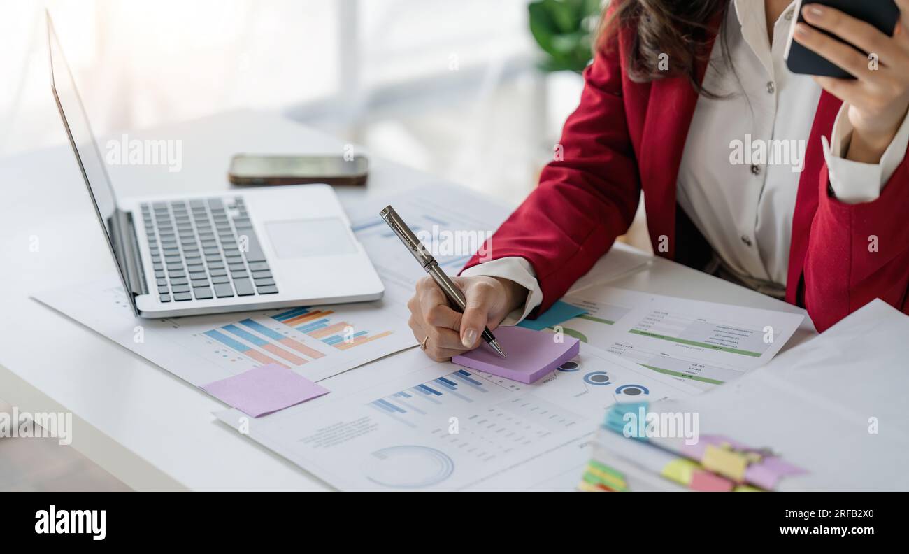 Nahaufnahme einer Geschäftsfrau, die am Arbeitsplatz eine Haftnotiz schreibt Stockfoto