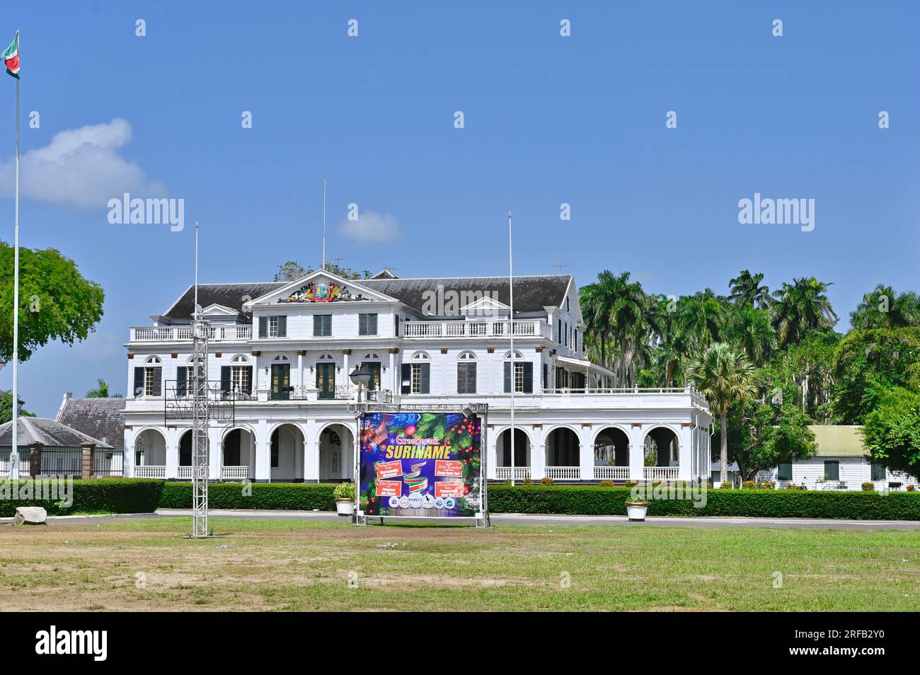 Der Präsidentenpalast von Suriname in der Hauptstadt Paramaribo. Davor ein Banner, das den Besuchern frohe weihnachten und ein erfolgreiches neues Jahr wünscht Stockfoto