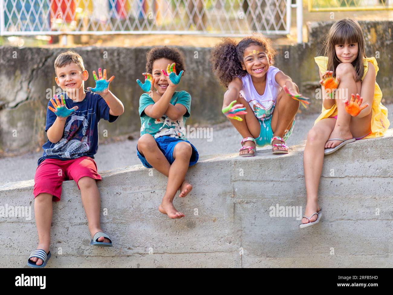 Eine Gruppe fröhlicher, multikultureller Kinder, die zusammen spielen und bemalte Hände zeigen Stockfoto