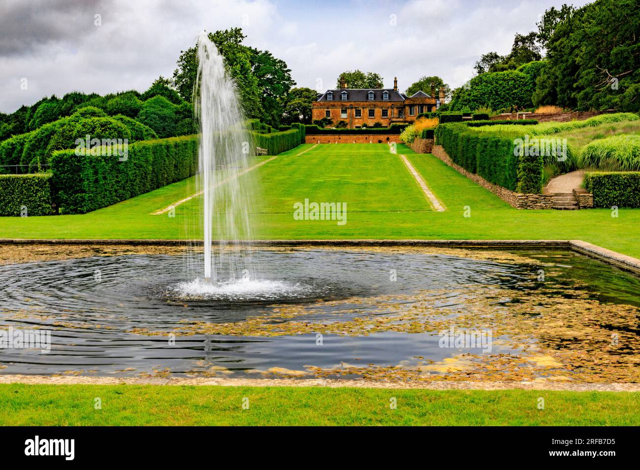 Der lange Spaziergang und der Brunnen mit dem Hadspen House Hotel im „The Newt in Somerset“, nr Bruton, England, Großbritannien Stockfoto