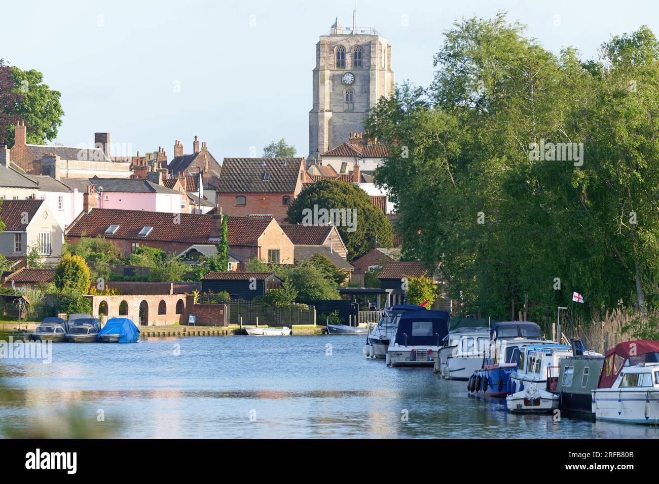 Blick auf festgemachte Boote und die Kirche auf dem Fluss Waveney in Beccles, Suffolk, England, Großbritannien Stockfoto