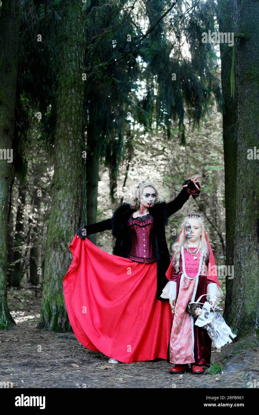Eine Frau in Form eines Vampirs oder einer Zauberin beißt eine Prinzessin in märchenhaftem Make-up und mittelalterlichem Kleid. Halten Sie Ausschau nach Halloween. Mutter A. Stockfoto