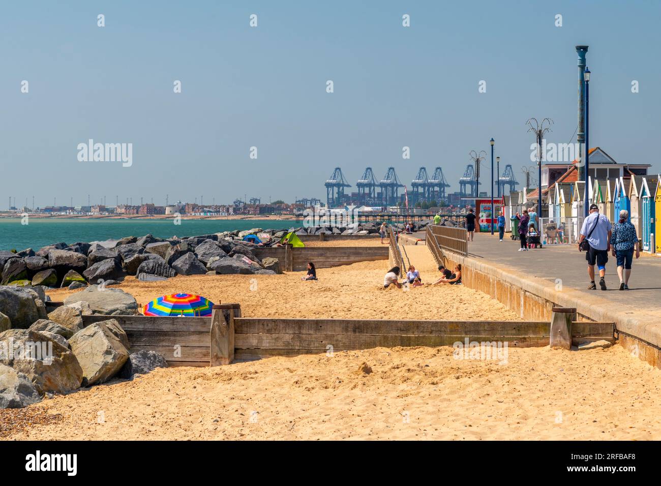 UK, England, Suffolk, Felixstowe, Beach mit Backbordkränen im Hintergrund Stockfoto