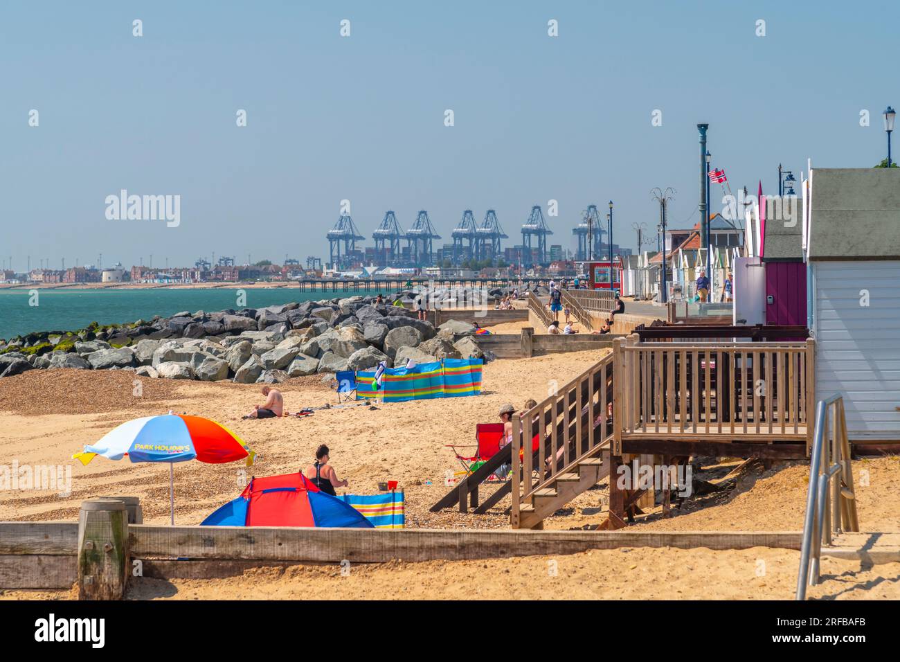 UK, England, Suffolk, Felixstowe, Beach mit Backbordkränen im Hintergrund Stockfoto