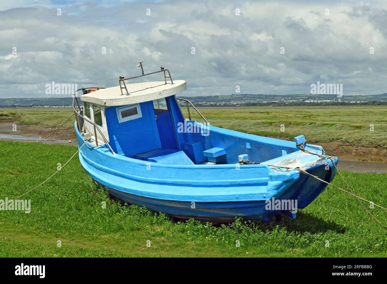 Ein Foto des mittlerweile weltberühmten „Blue Boat“, das an einem sonnigen Tag an der Küste auf den Ebenen von Penclawdd auf der Gower-Halbinsel festgemacht ist Stockfoto