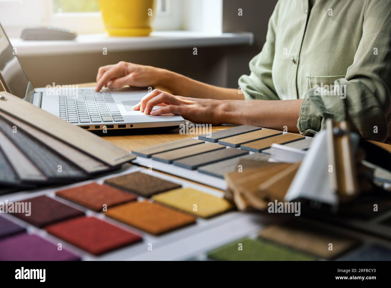 Innenarchitekt, der im Büro an einem Laptop arbeitet. Entwerfen Sie Materialproben auf dem Schreibtisch Stockfoto