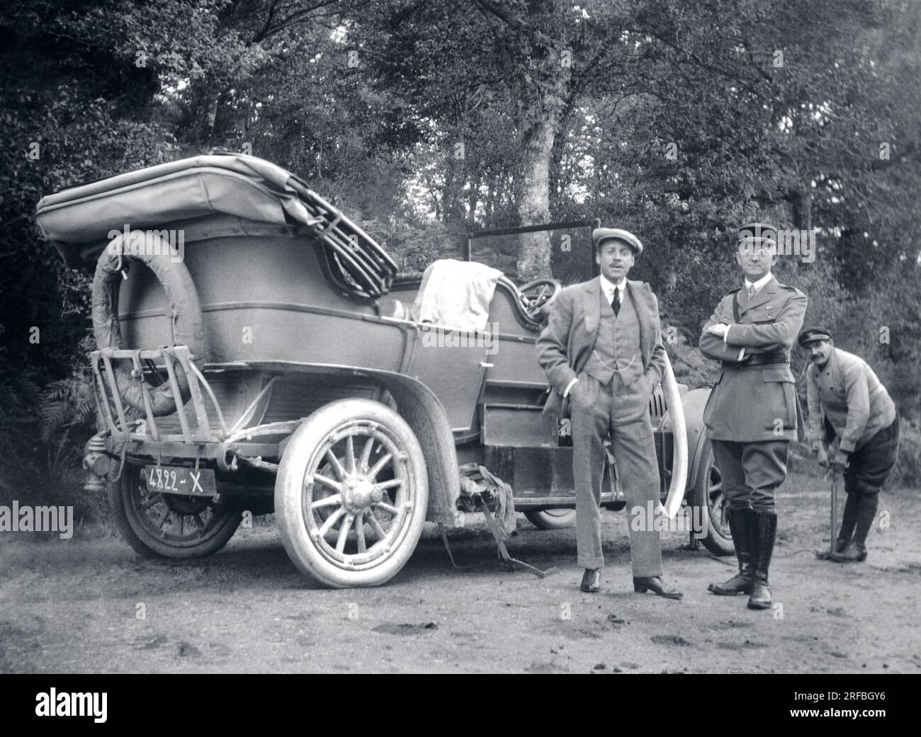 UN homme et un militaire en uniforme posant devant leur voiture en panne. Le Chauffeur actionne la pompe pour regonfler le pneu. Frankreich, Fotografie, 1917. Stockfoto