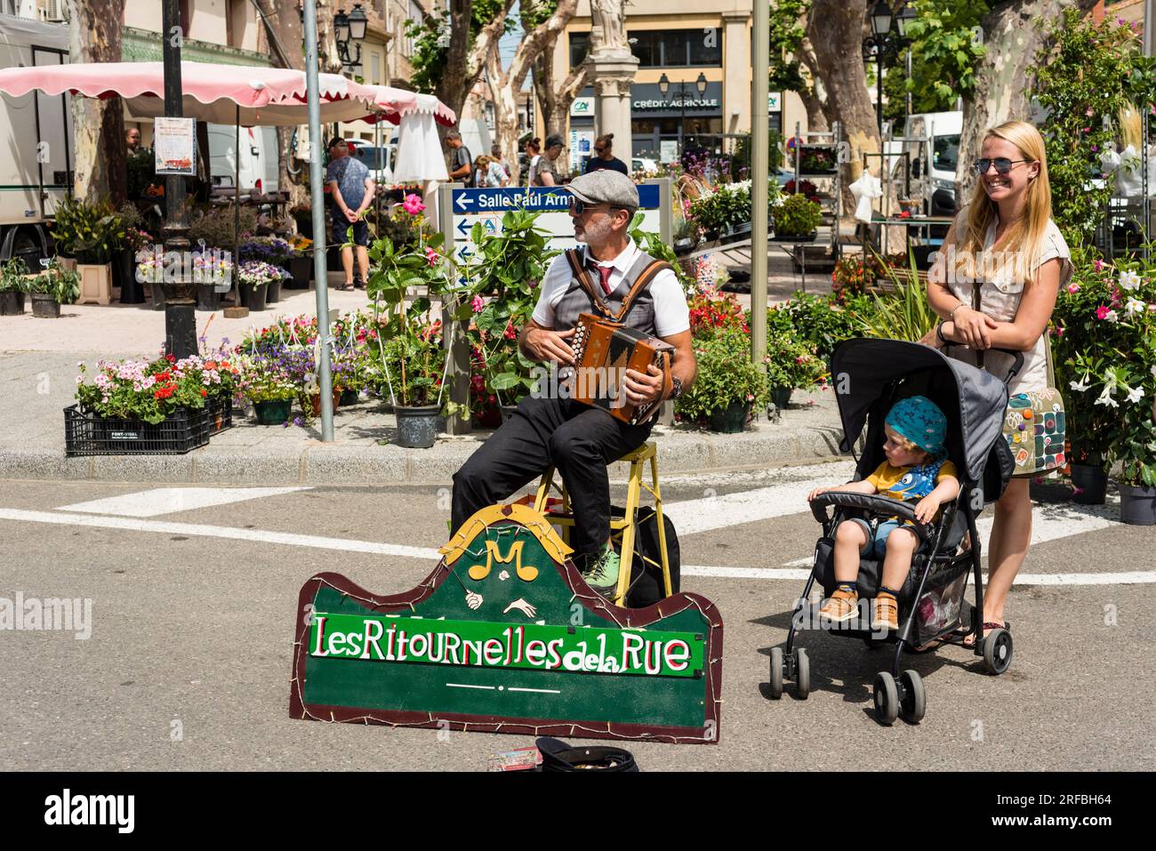 Stree Musiker und junge Frau mit Kleinkind im Kinderwagen, Marseillan, Herault, Occitanie, Frankreich Stockfoto