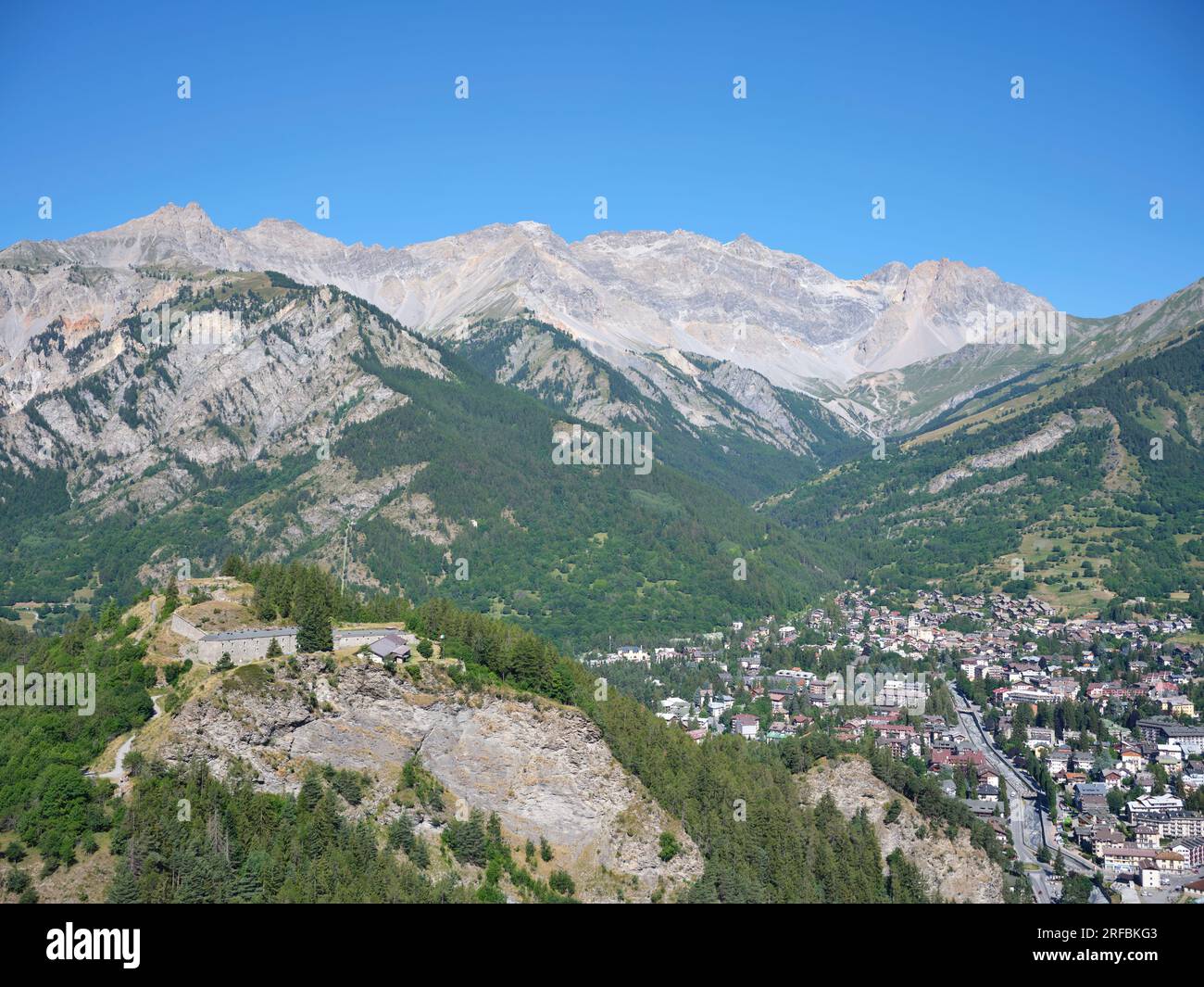 LUFTAUFNAHME. Die Stadt Bardonecchia im Susa-Tal mit Rocca Bernauda (3225m) in der Ferne und Bramafam-Fort auf der linken Seite. Piedmont, Italien. Stockfoto