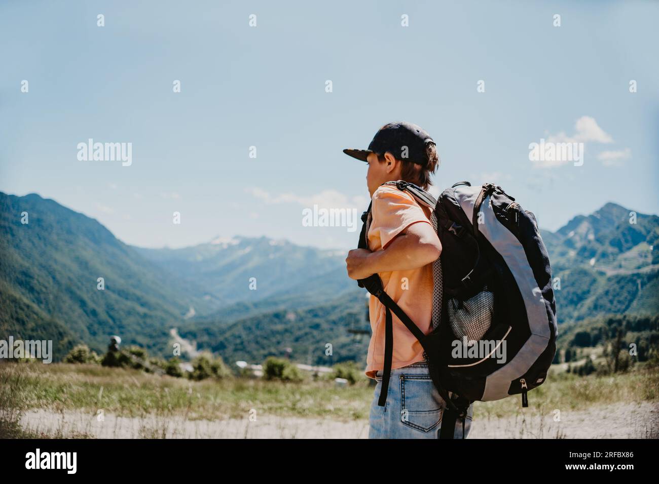 weißer Touristenjunge mit Rucksack in den Bergen. Hochwertiges Foto Stockfoto