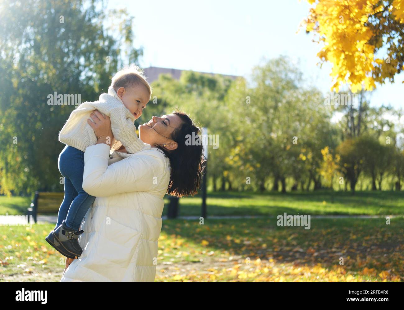 Kaukasische junge Mutter spielt oben werfen in der Luft lustige cute adorable toddler Boy. Mutter und Sohn Spaß im Herbst park mit gelben Blättern. Fami Stockfoto