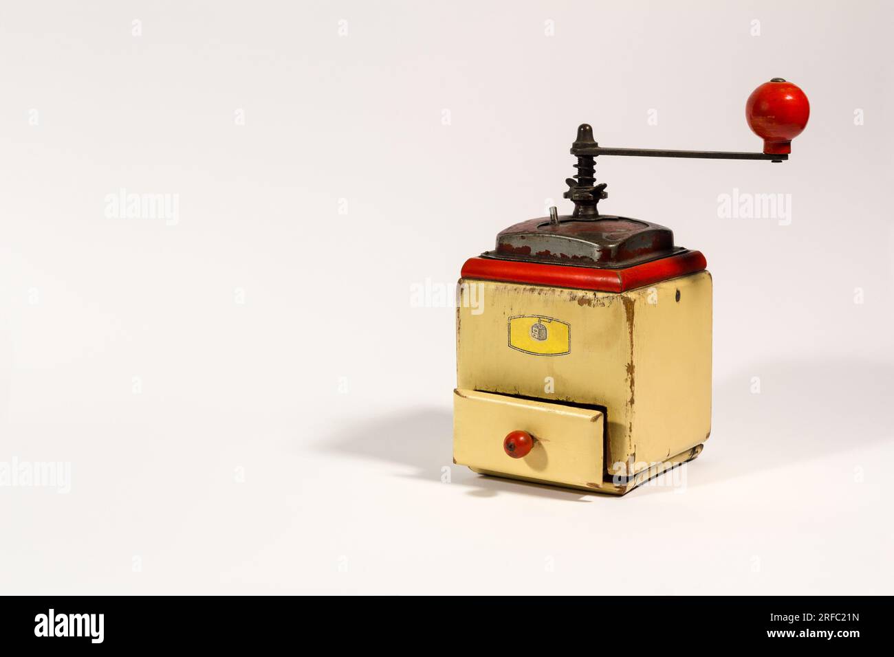 Alte hölzerne manuelle Kaffeemühle mit rotem Griff auf weißem Hintergrund und Kopierbereich. Stockfoto
