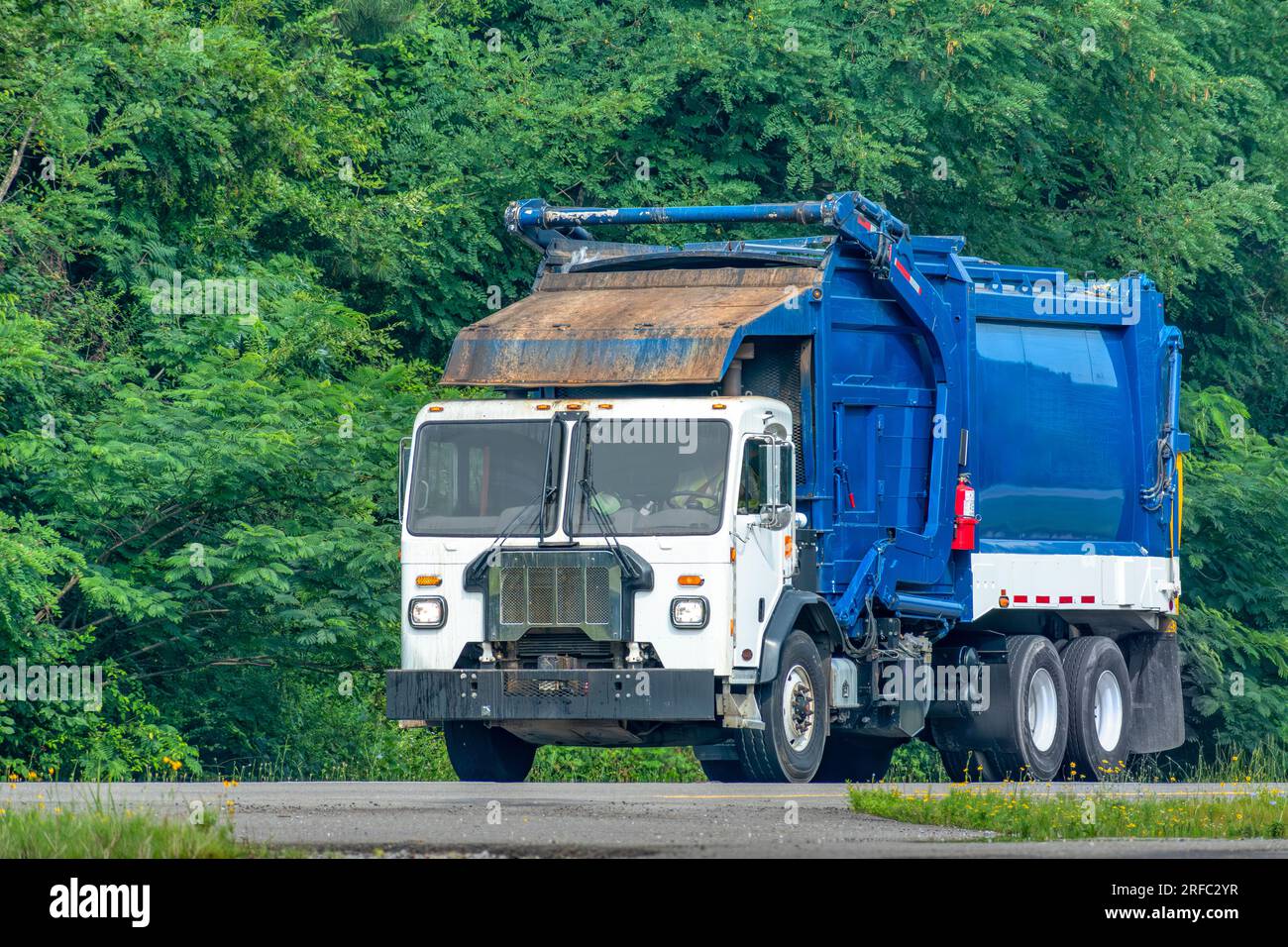 Horizontale Aufnahme eines blau-weißen Müllwagens auf der Autobahn. Stockfoto