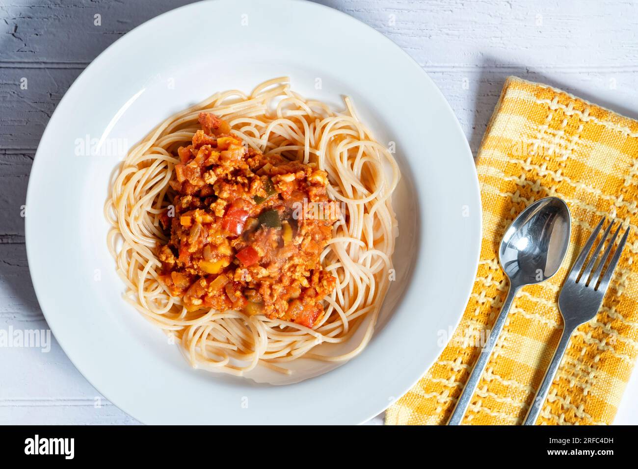 Eine Schüssel Ragu Bolognaise, serviert auf einem Bett mit Spaghetti. Eine Portion wird auf einen Tisch in einer tiefen weißen Schüssel gestellt Stockfoto