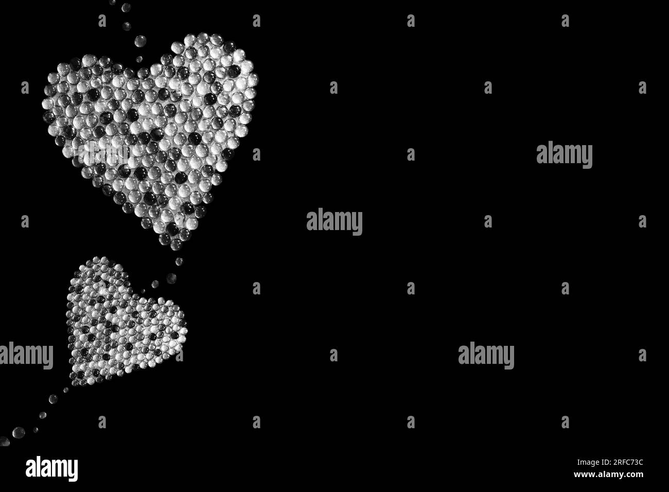 Zwei Herzen aus Steinen, isoliert auf schwarzem Hintergrund. Schwarzweißbild. Gedicht-Hintergrund. Valentinstag. Weihnachten. Liebesmotiv. Stockfoto