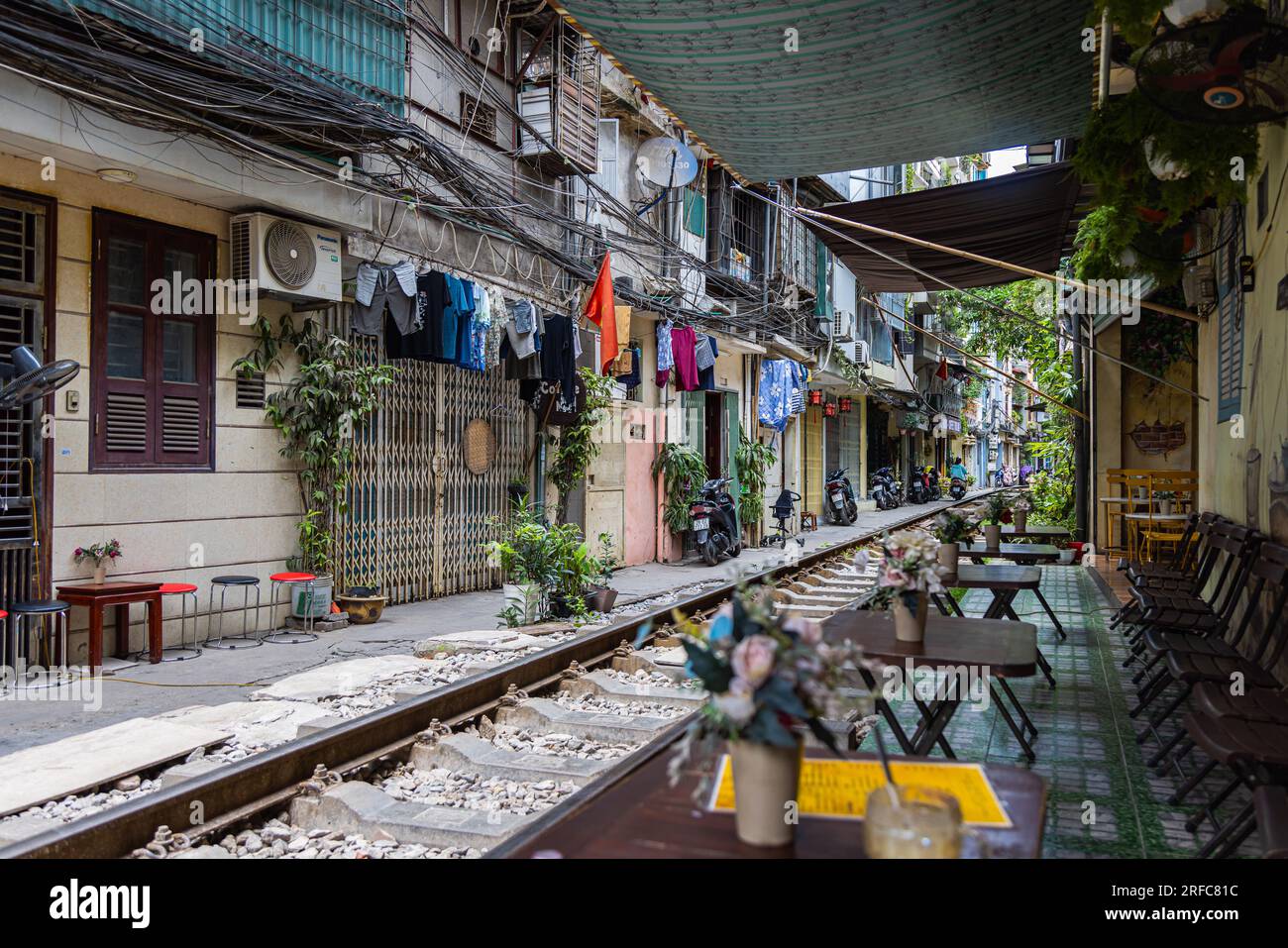 Hanoi, Vietnam - 28. Mai 2023: Train Street in Hanoi ist eine schmale, belebte Gasse mit Gleisen. Dicht gestrickte Häuser, mit Pflanzen geschmückt, sind Zentimeter entfernt f Stockfoto