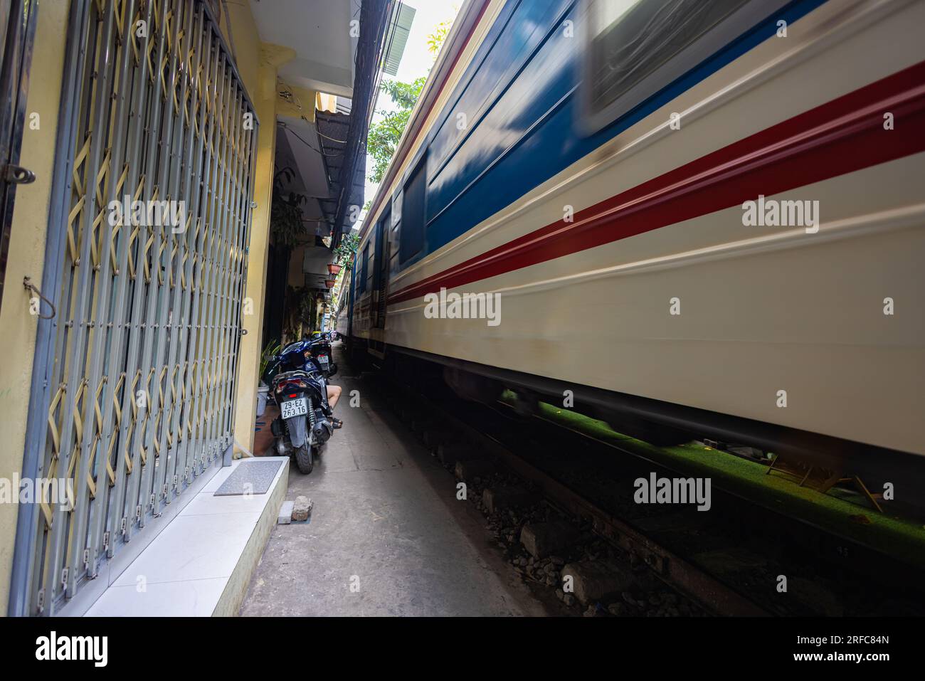 Hanoi, Vietnam - 28. Mai 2023: Train Street in Hanoi ist eine schmale, belebte Gasse mit Gleisen. Dicht gestrickte Häuser, mit Pflanzen geschmückt, sind Zentimeter entfernt f Stockfoto