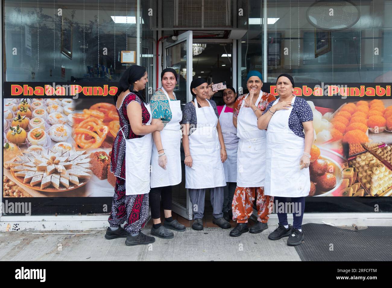 Punjabi-Indianerinnen, wahrscheinlich Sikhs, kommen aus ihrem Lebensmittelladen, um sich eine Hindu-Parade vom Ozone Park nach Jamaika anzusehen, um ihr Feuerspaziergang-Puja aufzuführen Stockfoto Punjabi-Indianerinnen, wahrscheinlich Sikhs, kommen aus ihrem Lebensmittelladen, um sich eine Hindu-Parade vom Ozone Park nach Jamaika anzusehen, um ihr Feuerspaziergang-Puja aufzuführen Stockfoto