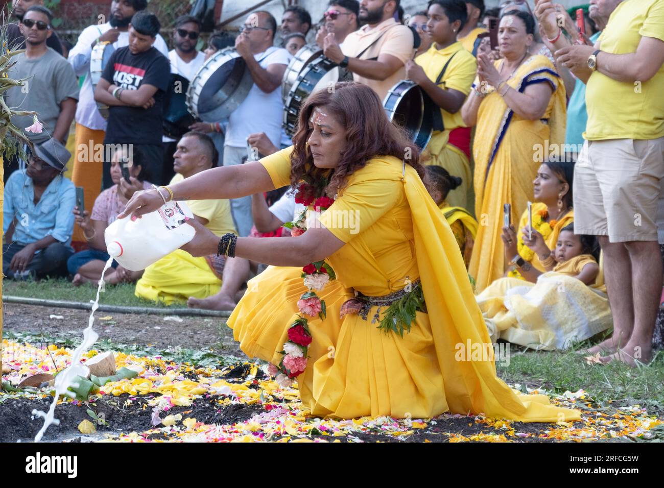 Kurz vor dem Thimithi-Feuer gießt eine hinduistische Frau Milch, ein Symbol für Geburt, Reinigung und Erhaltung. In Jamaika, Queens, New York. Stockfoto