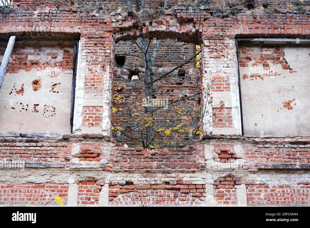 Gewölbte Fensteröffnungen eines zerstörten verlassenen Gebäudes. Gebrochene alte Bögen eines verlassenen alten Gebäudes. Horizontales Foto Stockfoto