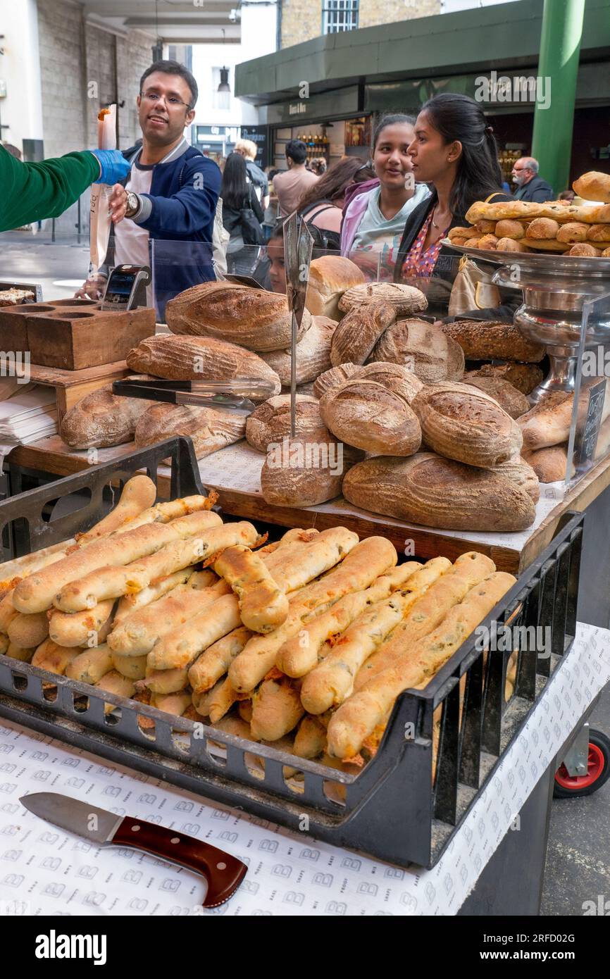 Brotmarktstand „BROT AHEAD“ mit Kunden, die ein frisches Baguette am Brotmarktstand kaufen, zeigt den Borough Market Southwark London UK Stockfoto
