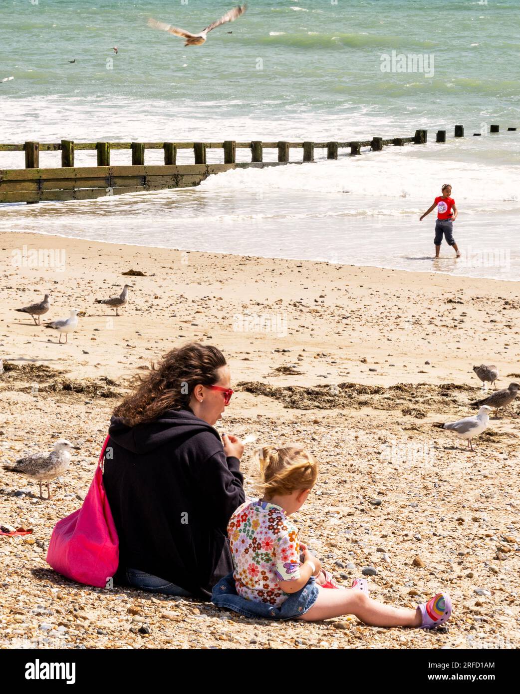 Promenade und Strand in Littlehampton, West Sussex, Großbritannien, im Sommer; zeigt Touristen in der Sonne und eine Mutter und Tochter am Strand Stockfoto