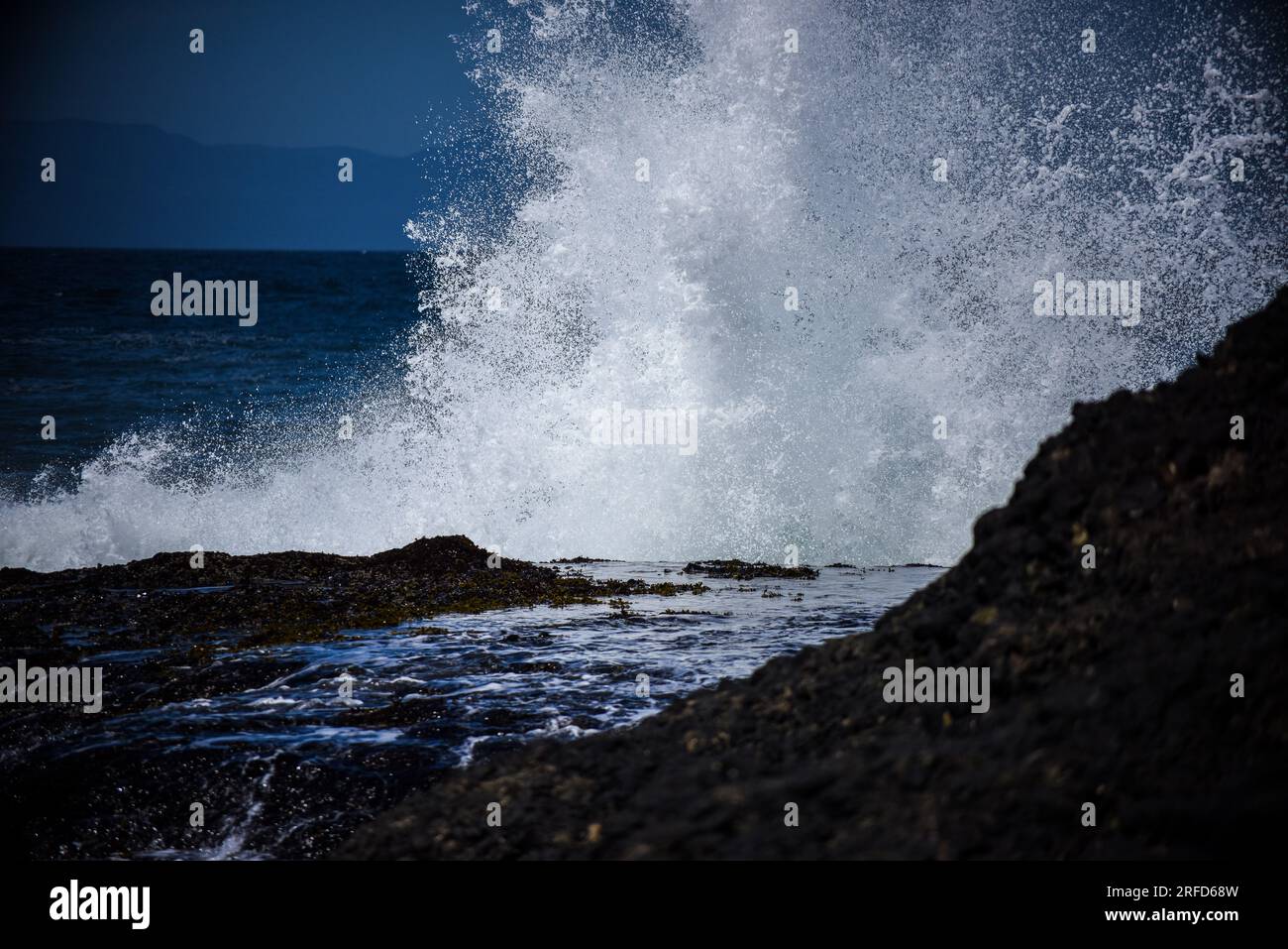 Eine Welle stürzt über einem Gezeitenbecken ab Stockfoto
