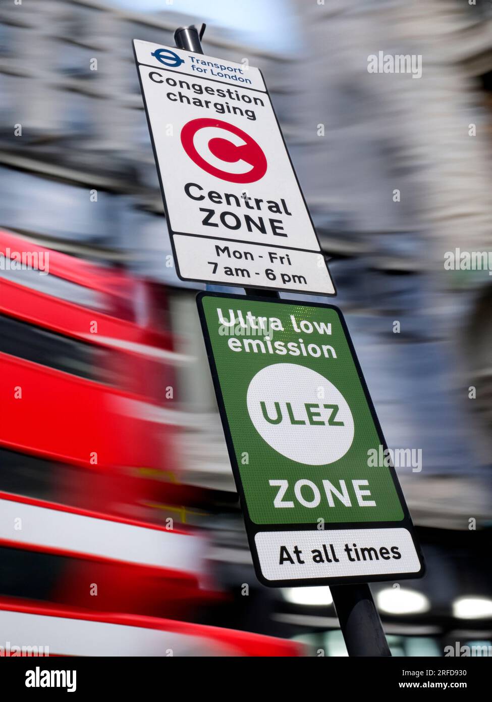 ULEZ-ZONE VERKEHRSZEICHEN TFL Stadtgebiet London Stadtmitte Hintergrund Verkehrsstau/Emission Charge London Zone Schild mit ULEZ-Schild für extrem emissionsarme Zone gegen verschwommenen Verkehr und Stadtgebäude London UK Stockfoto